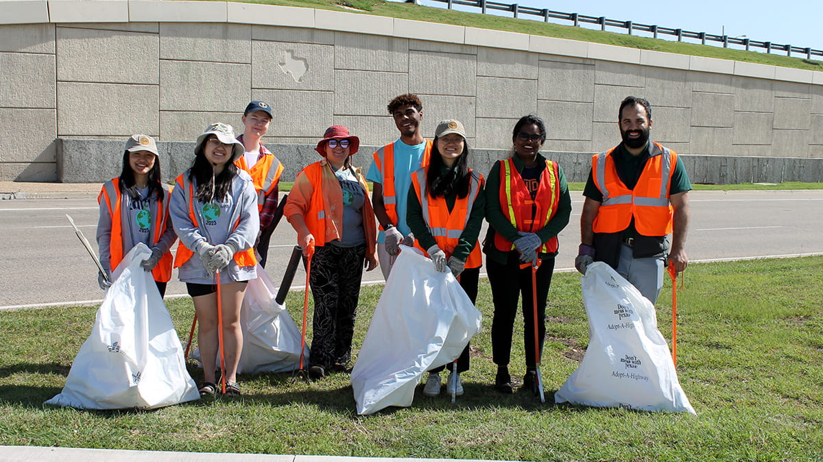 Participants in the highway cleanup event pose with trash bags.